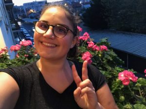 Selfie de Raquel devant des fleurs roses sur son balcon.