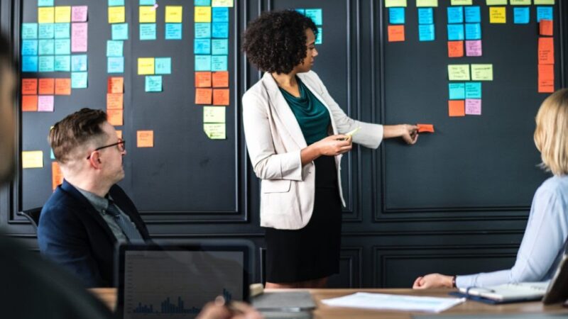 Femme collant un post-it sur un mur.
