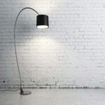 Photo de lampe de bureau noir sur un bureau en marbre gris, dans le fond un mur en brique blanche dans une style industriel